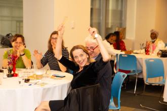 A woman raises her hands as she is acknowledged by attendees. 