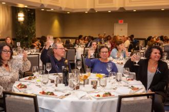 4 people at a table raise a glass in a toast 