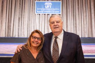 A man and woman take a photo in front of a stage 