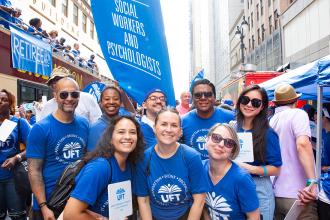 A group of parade goers pose for a photo all wearing blue