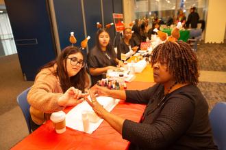 A teacher gets her nails painted by a student
