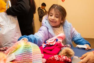 A young student smiles while getting to pick out winter attire 