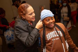 A woman helps a student with a new hat 