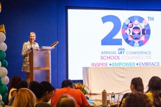School Counselors Chapter Leader Rosemarie Thompson stands on then stage and welcomes attendees