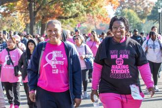 Two UFT members at the Queens Making Strides Walk on Oct. 20, 2024 smile for a photo while walking. 