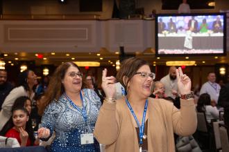 Two women at the 2024 UFT Paraprofessional Festival and Awards Luncheon react to the keynote address. 