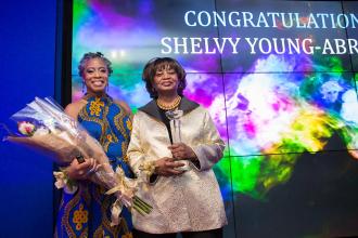 A woman on the right accepts an honor from the woman on the left