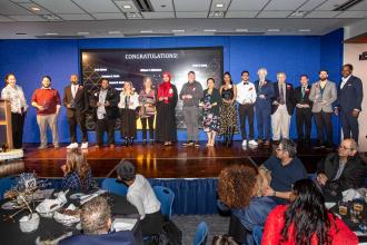 A group of award winners pose on stage for a photo opportunity 