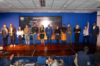 A large group of award winners pose on stage for a photo