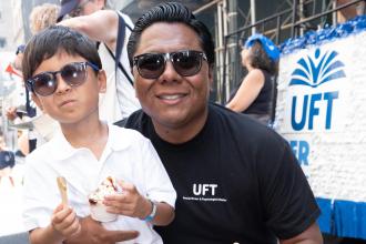 A man poses and smiles for a photo with his son who is holding ice cream
