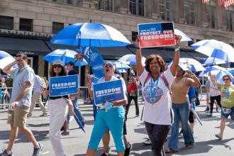 A group of members walk down the street with signs and chanting 