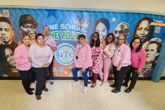 A group of staff at a public school in Queens wear matching pink attire for breast cancer awareness.