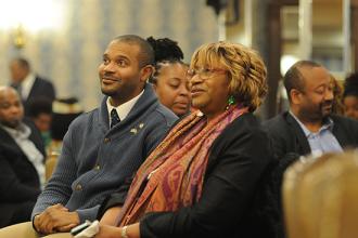 A man and and woman sit together and listen to a speech