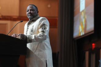 A man looks out to the crowd while speaking at a podium