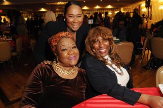 Three women pose for a photo at a table. 
