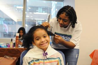 A woman works on the hair of a child