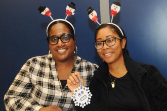 Two teachers smile for a photo while showing off one of their crafts at the UFT/Coalition for the Homeless holiday toy drive and celebration on Dec. 7, 2024. 