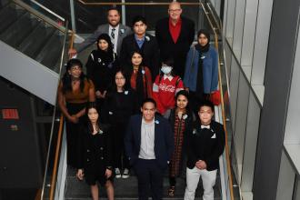A group of award winners take a photo on the stairs. 