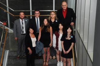 A group of award winners take a photo on the stairs. 