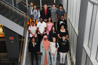 A group of award winners take a photo on the stairs. 