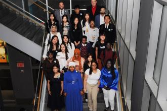 A group of award winners take a photo on the stairs. 