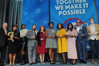 A group of award winners pose on stage for a photo. 