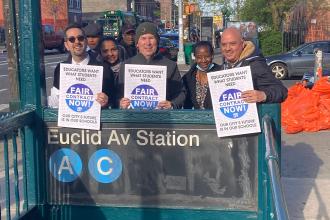 A group of four members hold their signs by a subway entrance 