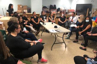 A group of staff members gather together in a circle for a discussion 