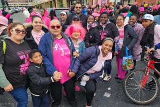 A large group of marchers pose for a photo and all of them are wearing pink attire.