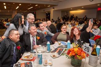  A group of men and women gather at a table for a "selfie"