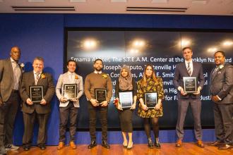 A group of award winners pose on the stage 