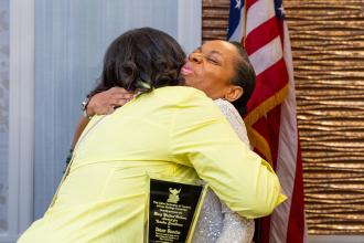 Two women share a hug after one of them receives an award. 