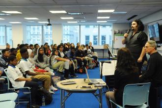 Group of students watching man with microphone