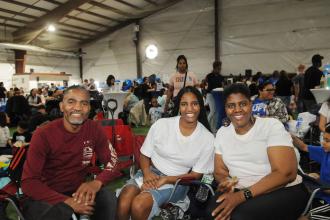 A teacher and her family take a group photo while seated during the 2025 UFT Family Day. 