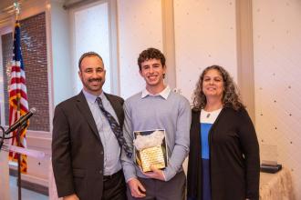 UFT Jewish Heritage Committee Chair Jason Goldberg (left) and UFT Educational Liaison Laurie Lubman present the Student of the Year Award to Yonathan Bar of the Bronx HS of Science at the 2024 UFT Jewish Heritage Committee Tikkun Olam Awards Dinner on Dec. 5, 2024. 
