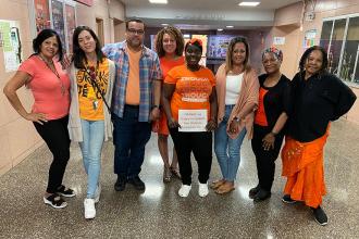 A group of staff members pose together wearing orange