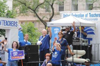 UFT President Michael Mulgrew waves from atop the union float as it passes the reviewing stand on Fifth Avenue during the 2025 NYC Labor Parade