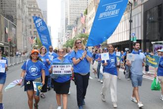 Throngs of UFT members carry banners displaying their union chapter names during the 2025 NYC Labor Parade. 