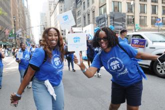 UFT members pose for a photo while holding UFT banners during the 2025 Labor Parade.