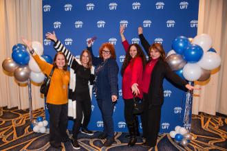 New retirees gather in front of a UFT backdrop for a group photo at the UFT New Retiree Luncheon on Dec. 5, 2024 at the Midtown Hilton