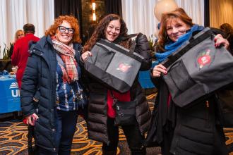 New retirees hold up their gift bags at the UFT New Retiree Luncheon on Dec. 5, 2024.