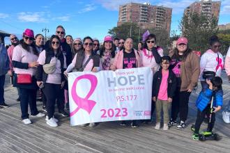 A group of marchers working in Brooklyn pose for a group photo during a breast cancer awareness march.