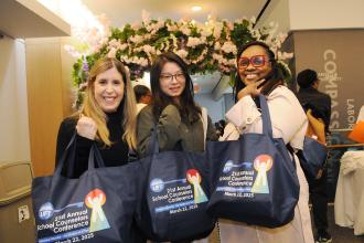 School counselors in attendance at the 2025 School Counselors Conference show off their tote bags. 
