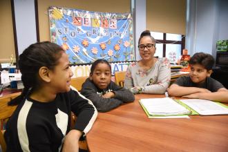 Teacher sitting at table with three students