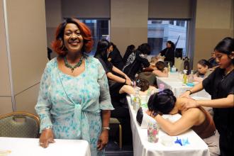 Teacher Andrea Lingstuyl beams as her CTE students at Queens Technical HS give massages in the exhibit hall at the 2025 UFT Spring Education Conference. 