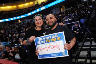 Two UFT members pose for a photo while holding a Fix Tier 6 campaign sign at the MVP Arena in Albany. 