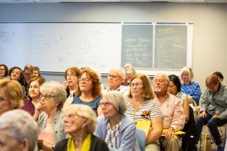 Retirees listen intently during the “New York City as Muse” workshop, where slides are shown of the city as viewed by famous artists like Edward Hopper and Keith Haring.