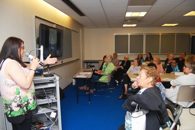Speaker at a mike in a room full of classroom attendees