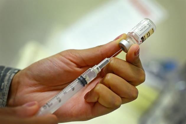 Hand holding a syringe pulling vaccination