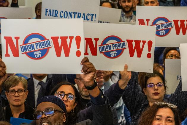Members hold up signs in support of fair contracts